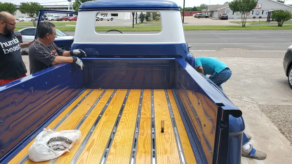 A new wood bed floor with polished chrome strips being fitted into the restored pickup