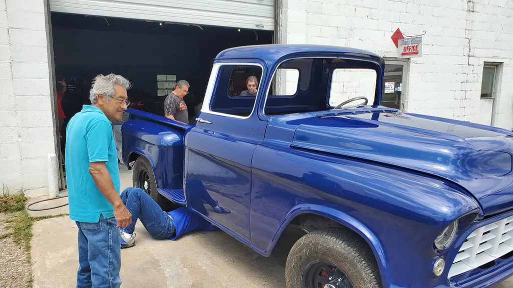 The crew at Edward's Auto Paint Shop standing with a finished restoration outside the bay