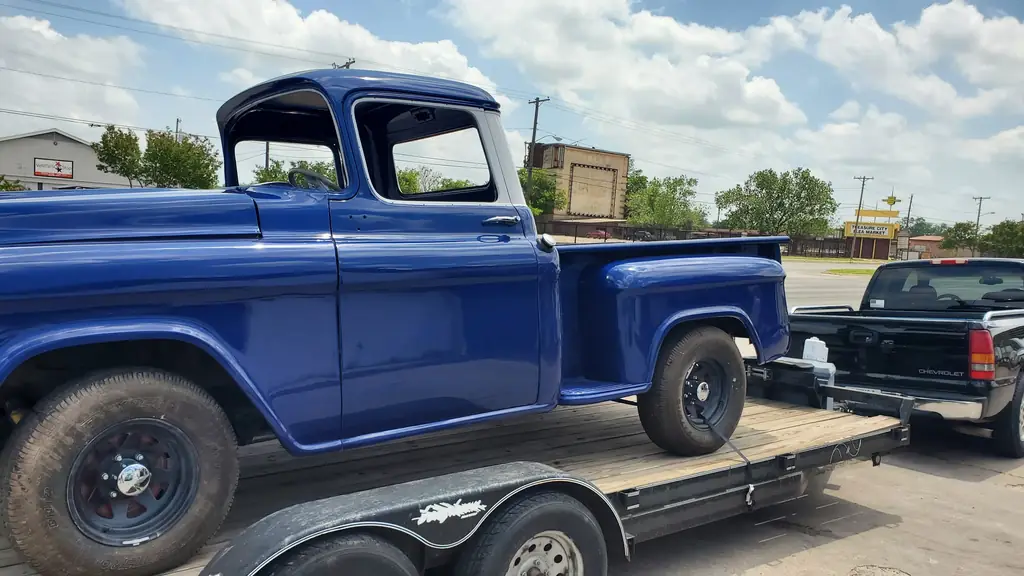 The restored deep blue two-tone 1950s Chevrolet 3100 stepside pickup in profile on the street in Waco