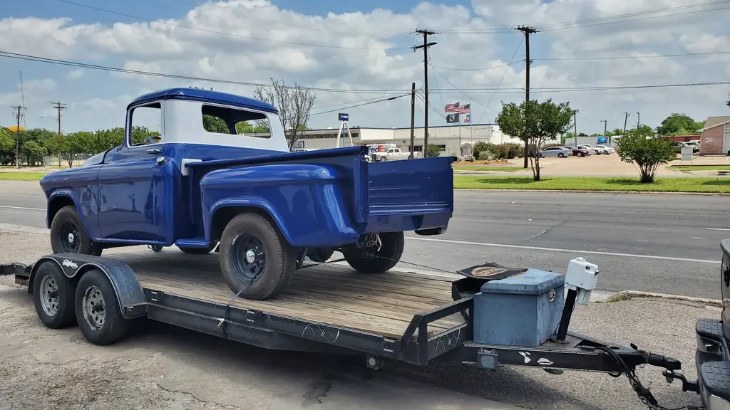 The finished pickup strapped to a flatbed trailer on La Salle Avenue with the Texas flag behind it
